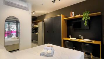 Une chambre d’hôtel avec un lit, un bureau, une télévision et un balcon.