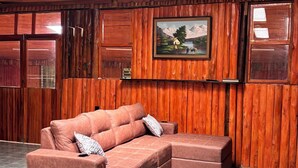 A room with wooden walls, a large window, a sofa, and a painting.