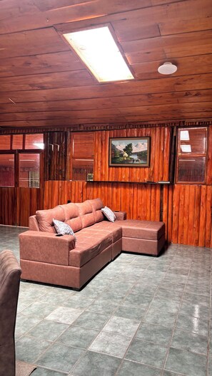 A room with wooden walls, a large window, a sofa, and a painting.