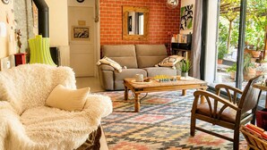 Ein gemütliches Wohnzimmer mit Sofa, Sessel, Couchtisch und Blick ins Freie.