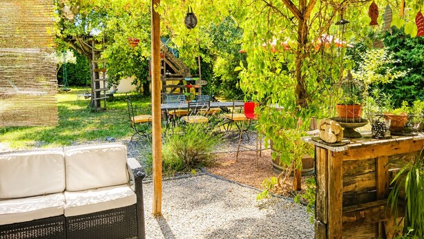 Ein überdachter Außenbereich mit Holz-Pergola, einem Schild mit der Aufschrift 'RODEO' und verschiedenen Kübelpflanzen.