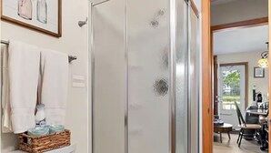 A bathroom with a glass shower enclosure, a toilet, and a wicker basket on the toilet. - Lakefront Cabin - Paddleboat, Paddleboards & Fishing Dock Included. Pet friendly (Lindstrom)