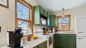 A kitchen with green cabinets, a white refrigerator, and a window with a view of trees. - Lakefront Cabin - Paddleboat, Paddleboards & Fishing Dock Included. Pet friendly (Lindstrom)