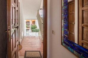 A hallway with a patterned rug, wooden doors, and a balcony with a railing. - GuestHost - Golfo Aranci Sunny Retreat Apartment with Terrace! (Golfo Aranci)