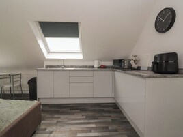 Una cocina compacta con tragaluz, microondas, cafetera y un reloj en la pared.