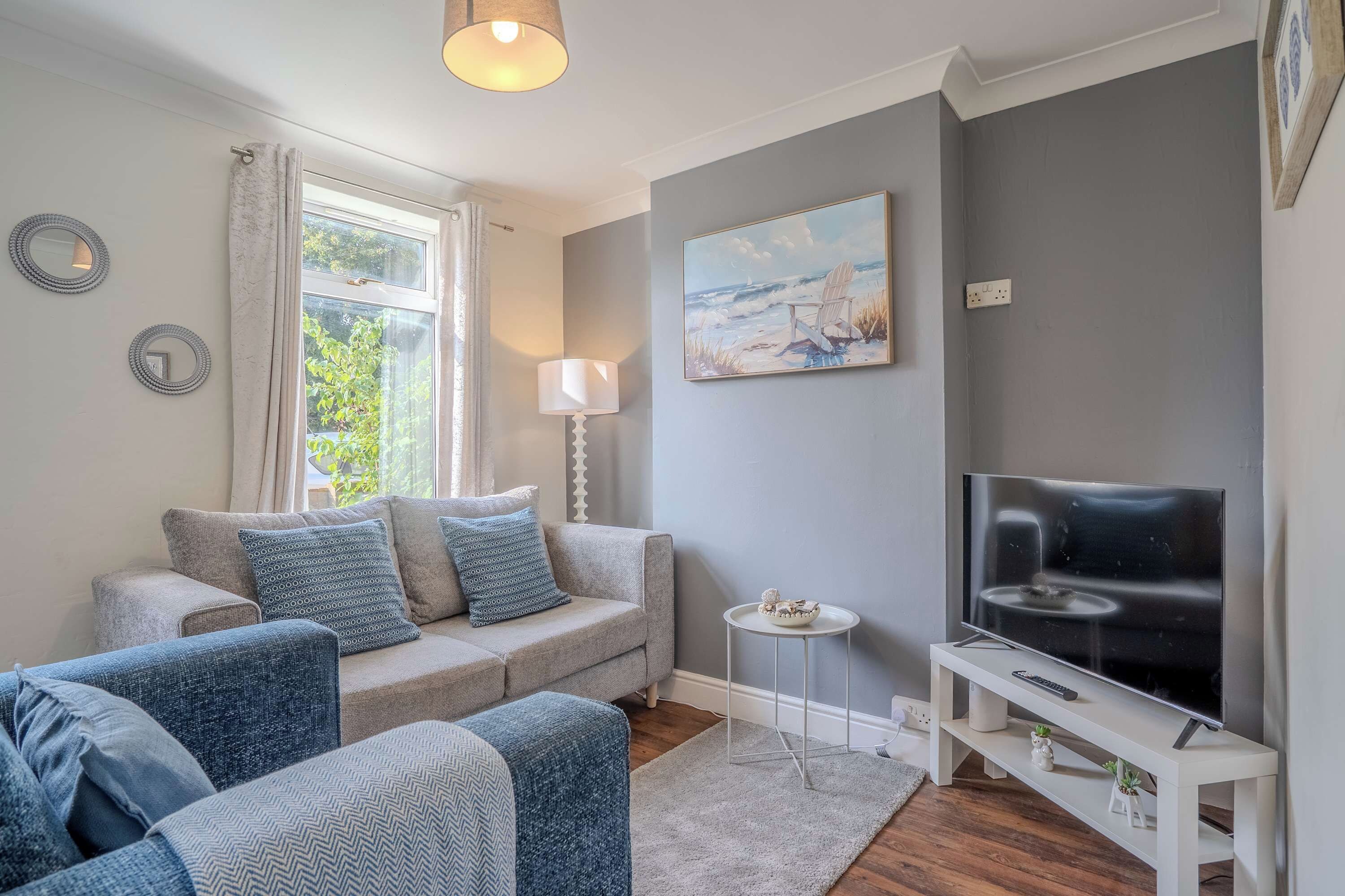 Ein Wohnzimmer mit einer Couch, einem Fernseher und einem Gemälde an der Wand.