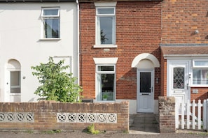 A two-story residential building with a white facade, a brick section, and a white picket fence. - 3 Bedroom Home Near Beach & Attractions (Great Yarmouth)