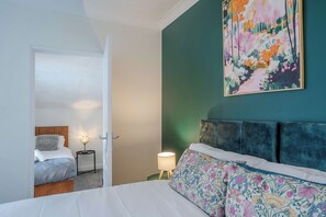 Une chambre à coucher avec un lit, une table de chevet, une lampe et un tableau au mur.