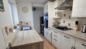 A modern kitchen with white cabinets, a wooden countertop, and a stainless steel range hood. - 3 Bedroom Home Near Beach & Attractions (Great Yarmouth)