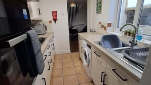 A compact kitchen with a washing machine, a sink, and a window. - 3 Bedroom Home Near Beach & Attractions (Great Yarmouth)