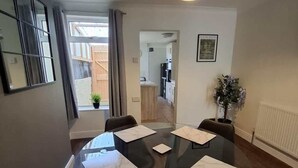 A modern dining area with a round table, black chairs, and a pendant light. - 3 Bedroom Home Near Beach & Attractions (Great Yarmouth)