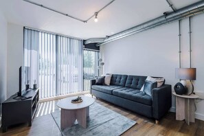 A modern living room with a sofa, a coffee table, and a TV stand.