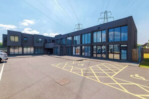 A modern building with large windows and a parking area marked with accessibility symbols.