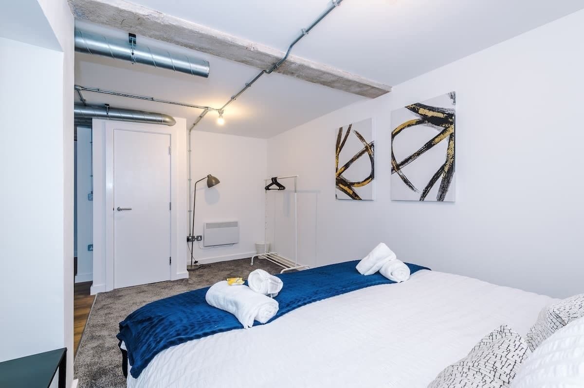 A hotel room with a bed, towels, a wardrobe, and a coat rack.