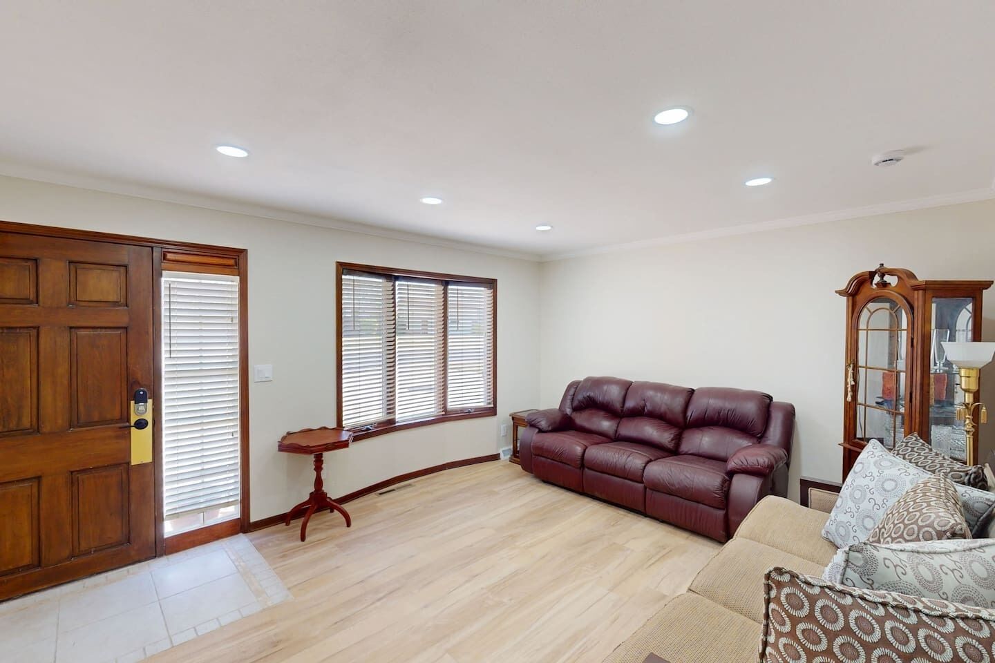 A living room with a leather sofa, a wooden cabinet, and a small table.