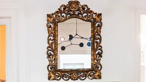 Une pièce dotée d’une cheminée, d’un miroir décoratif et de meubles recouverts d’un tissu vert.