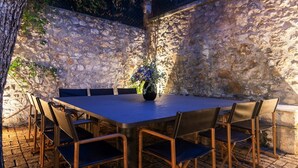 A stone wall with a table and chairs set up for dining.