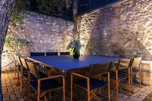 A stone wall with a table and chairs set up for dining.