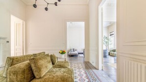 A room with a sofa, a patterned rug, and a chandelier.