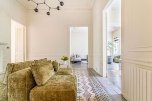 A room with a sofa, a patterned rug, and a chandelier.