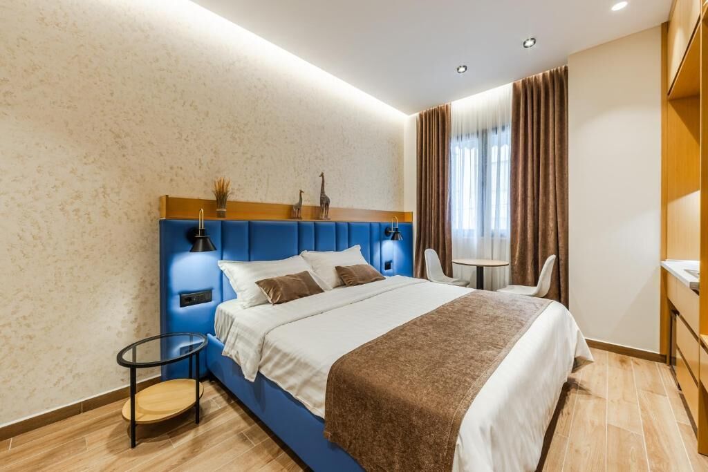 A modern hotel room with a large bed, a small round table, a chair, and a desk.