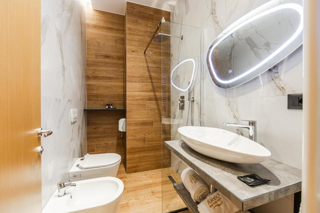 Une salle de bain moderne avec un meuble-lavabo en marbre, une cabine de douche en verre et des toilettes.