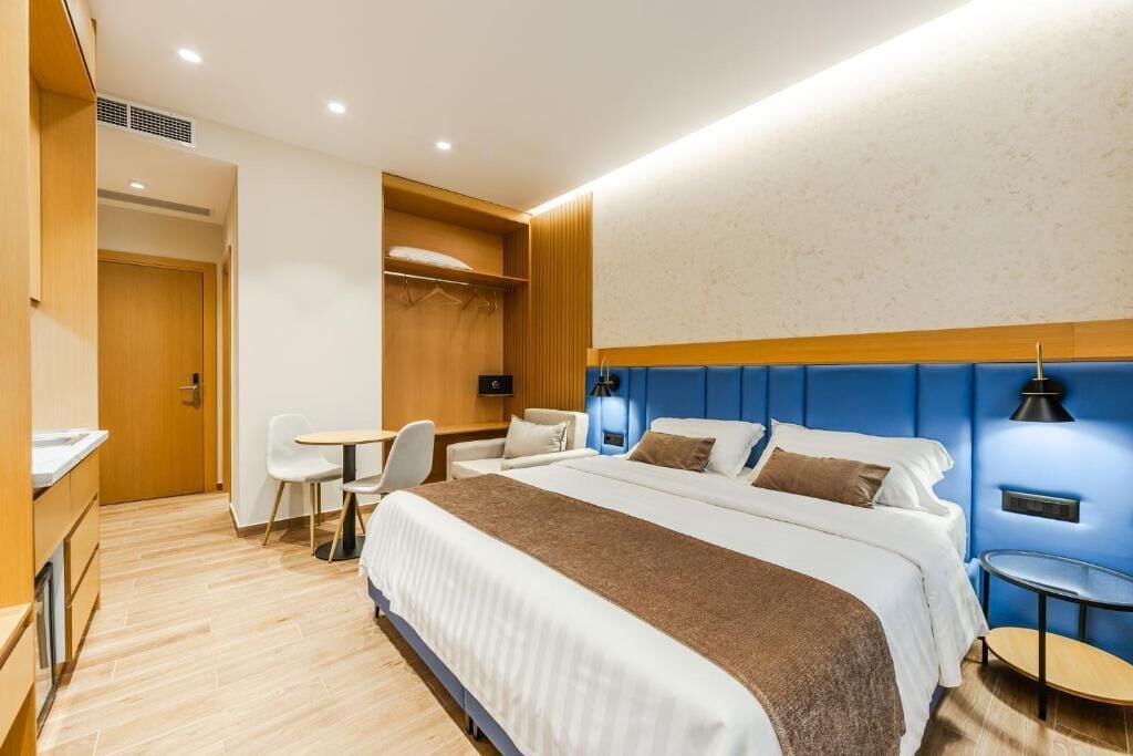 Quarto de hotel com cama, mesas de cabeceira, escrivaninha e uma cadeira.