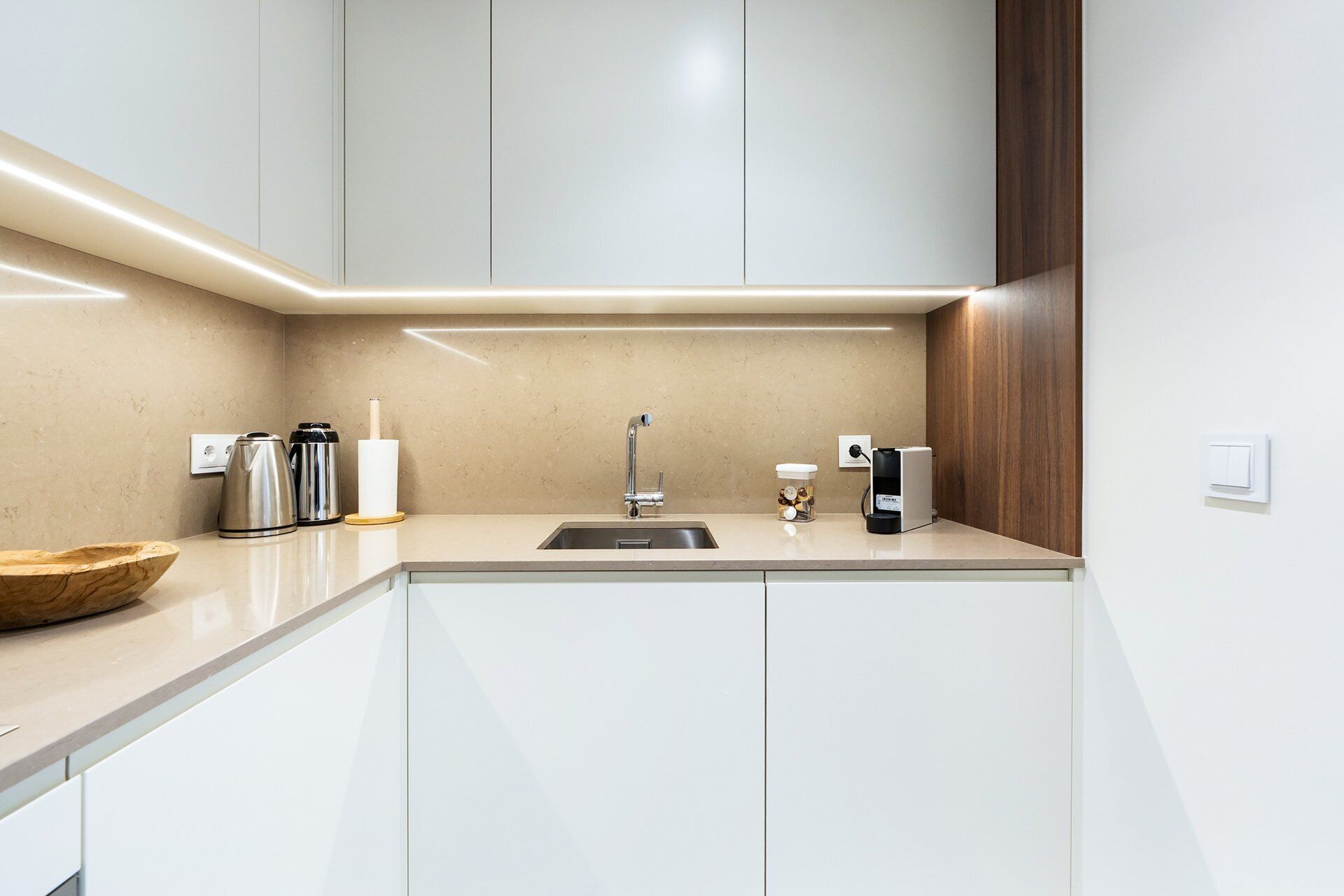 Eine moderne Küche mit Spüle, Edelstahl-Wasserkocher und Kaffeemaschine.