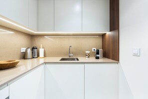 Eine moderne Küche mit Spüle, Edelstahl-Wasserkocher und Kaffeemaschine.