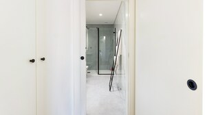 A white door leading to a bathroom with a glass shower enclosure and a towel rack. - GuestReady-Charming Gaia Retreat with Balcony (Vila Nova de Gaia)