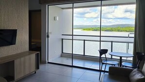 Una habitación con un gran ventanal corredera que da a un balcón con vistas a un lago y montañas.