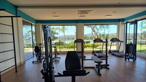 Un gimnasio con equipo de ejercicio, ventanas amplias y vistas al verdor.