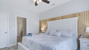 Une chambre à coucher avec un lit, une table de chevet, un ventilateur de plafond et un mur recouvert de panneaux en bois.