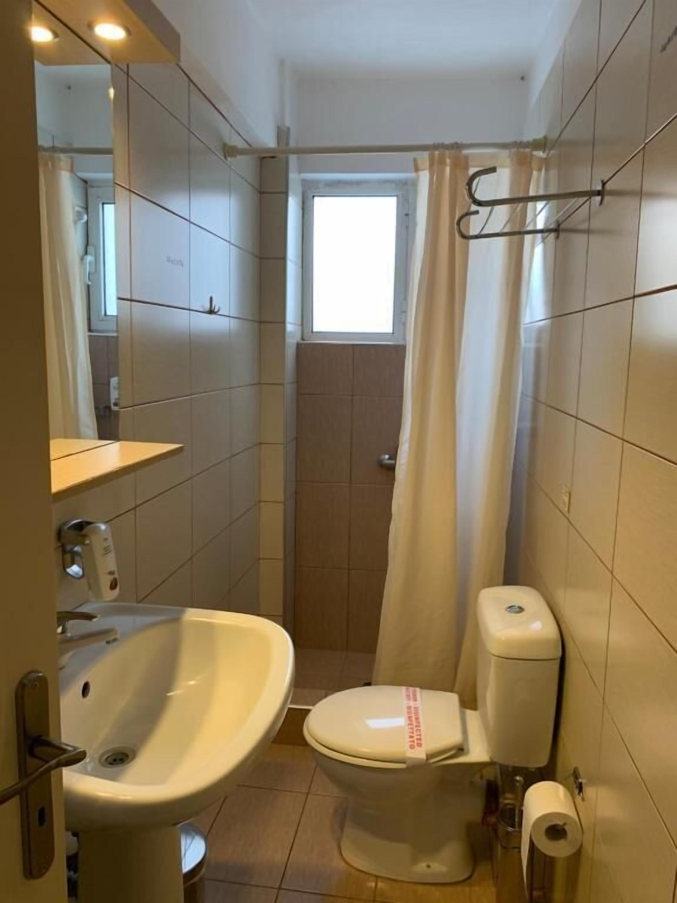 A small bathroom with a toilet, sink, and shower curtain.