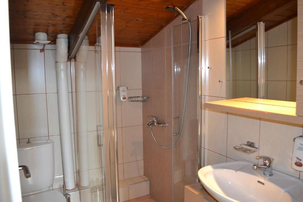 Egy fürdőszoba zuhanyzóval, WC-vel és mosdókagylóval.
