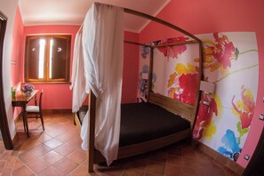 A single room with a bed, a window, a table with a chair, and a wall with colorful floral wallpaper. - Homerez - Spacious Villa with Pool in Segni (Segni)