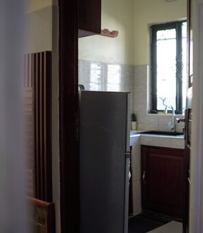A kitchen with a refrigerator, cabinets, and a window.