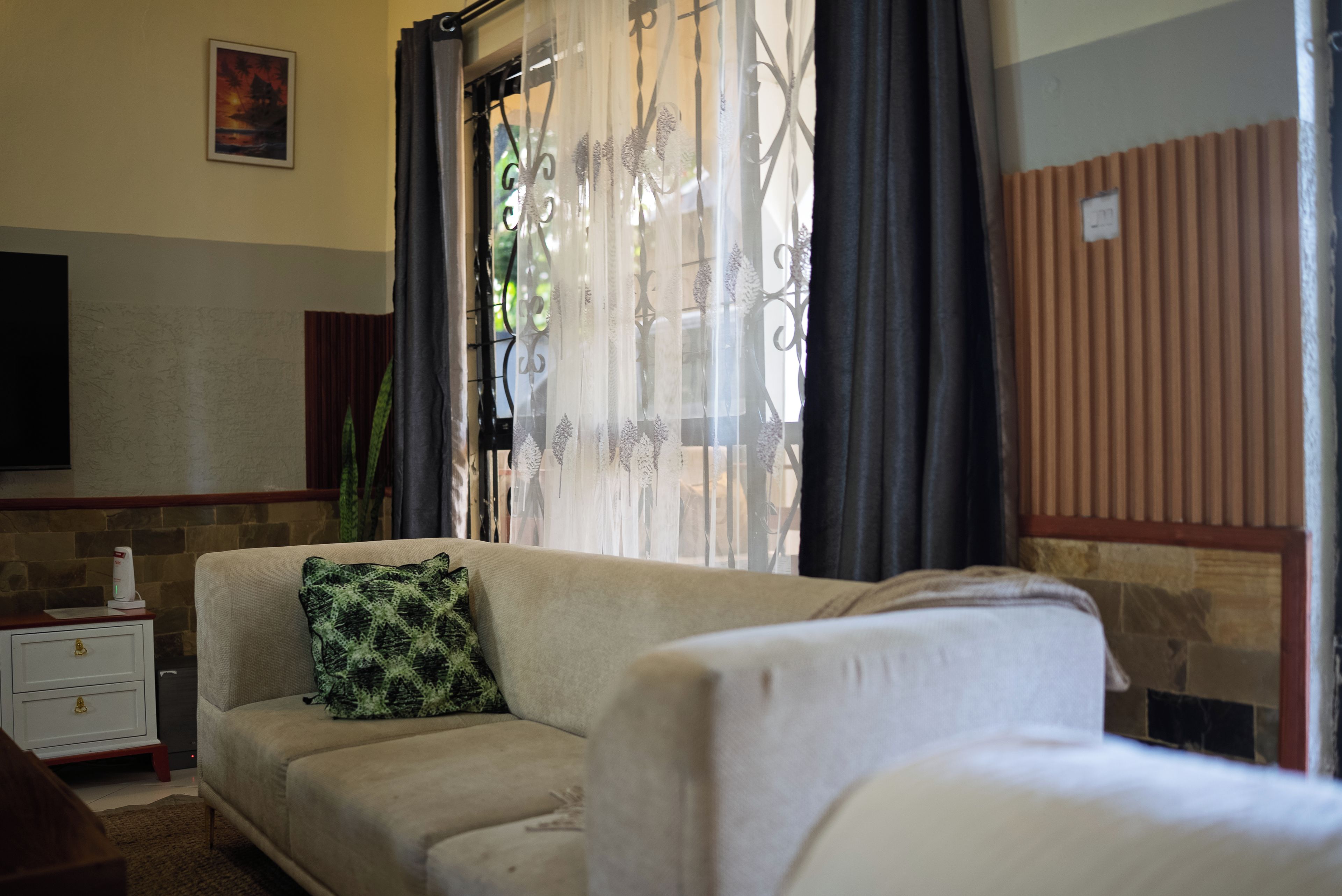 Ein Wohnzimmer mit einer Couch, einem kleinen Tisch und einem an der Wand befestigten Fernseher.