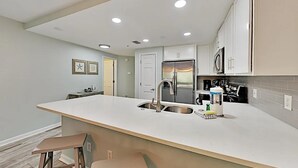 A modern kitchen with a large island, stainless steel appliances, and recessed ceiling lights. - Ciboney 1010 (Miramar Beach)