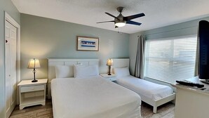 A hotel room with two beds, a ceiling fan, a framed picture on the wall, and a window with curtains. - Ciboney 1010 (Miramar Beach)