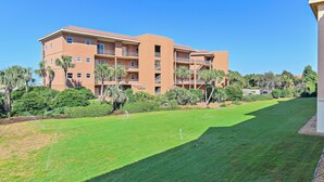 A multi-story building with balconies, surrounded by well-maintained lawns and palm trees. - Ciboney 1010 (Miramar Beach)