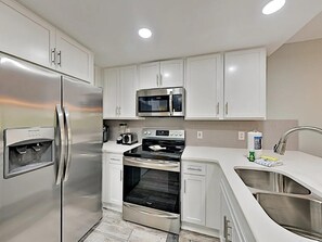 A modern kitchen with stainless steel appliances, white cabinetry, and a built-in oven. - Ciboney 1010 (Miramar Beach)