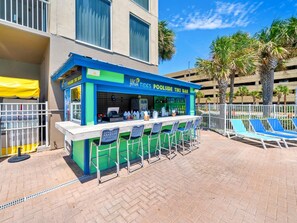 Eine Tiki-Bar mit Außenbereich und Blick auf den Pool.