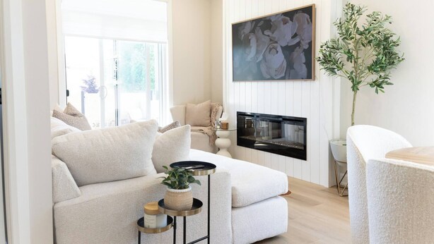 A living room with a sofa, a fireplace, a painting, and a plant.