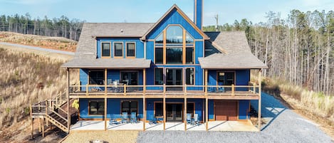 A two-story house with a balcony, a chimney, and a gravel driveway.