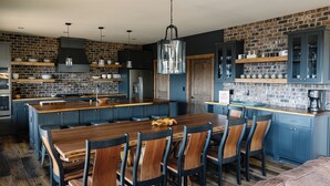 Una cocina moderna con una isla central, armarios oscuros y paredes de ladrillo visto.