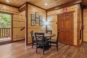 A wooden interior with a dining table and chairs, a fire extinguisher, and a door labeled 'FIRE RISER ROOM'. - A Happy Place | 8BR Cabin | Indoor Pool | GameRoom (Sevierville)