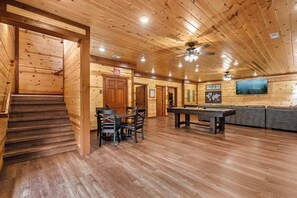 A wooden interior with a pool table, a sofa, and a staircase. - A Happy Place | 8BR Cabin | Indoor Pool | GameRoom (Sevierville)