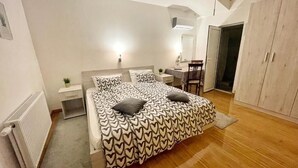 Quarto com cama, mesa de cabeceira, abajur e guarda-roupa.