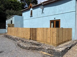 Un edificio con fachada azul claro, cerca de madera y base de piedra.